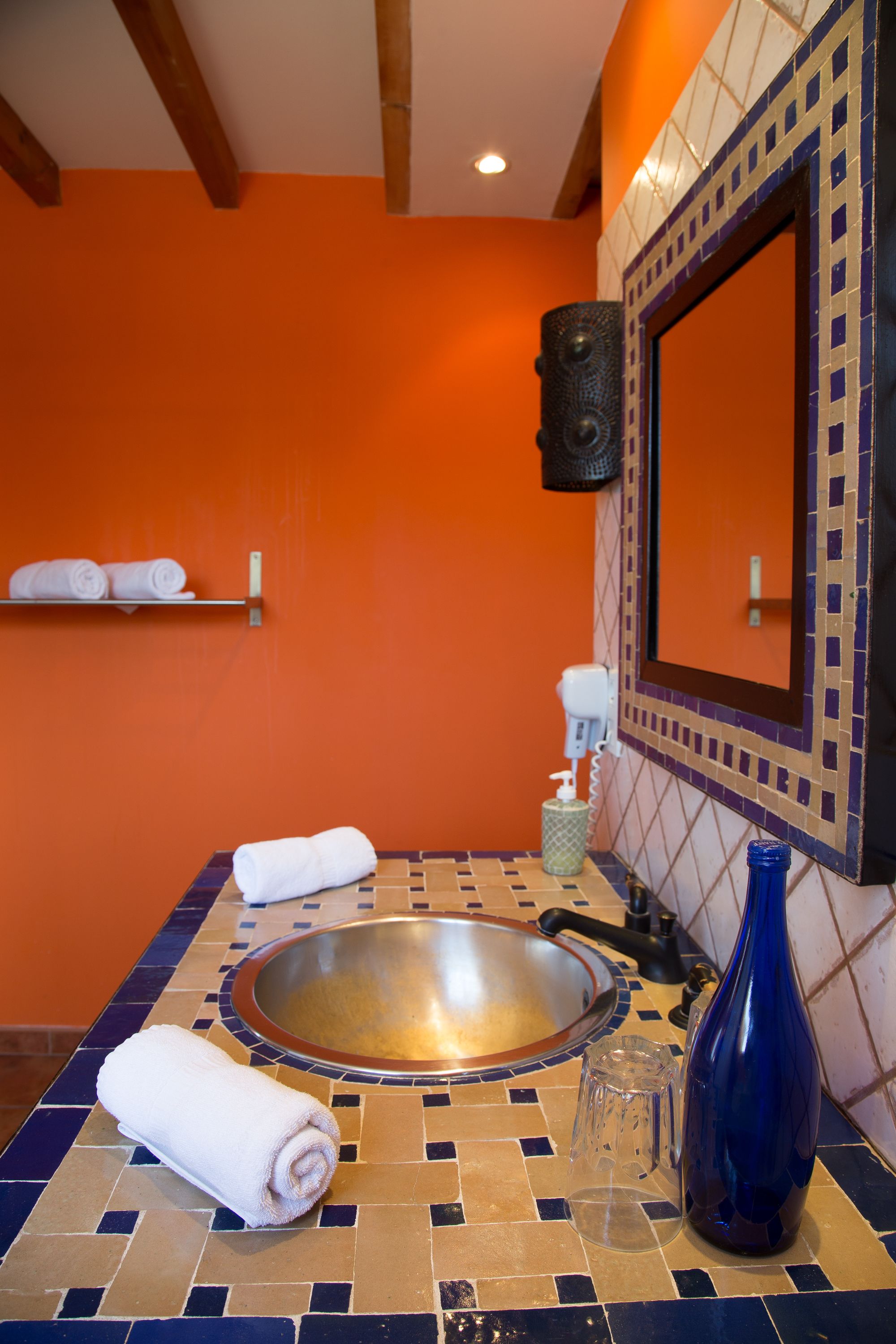 A bathroom with a tiled sink, a blue vase, and a towel on the counter.