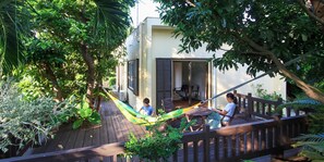 A wooden deck with a hammock, a wooden fence, and lush greenery. - Ishigakijima Cottage Kachibai (Ishigaki)