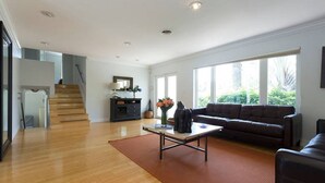 Un salon spacieux doté d’un parquet, d’un canapé marron foncé et d’une table basse.