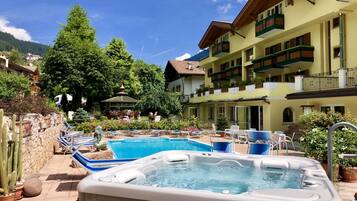A hotel courtyard with a swimming pool, a hot tub, and lounge chairs.