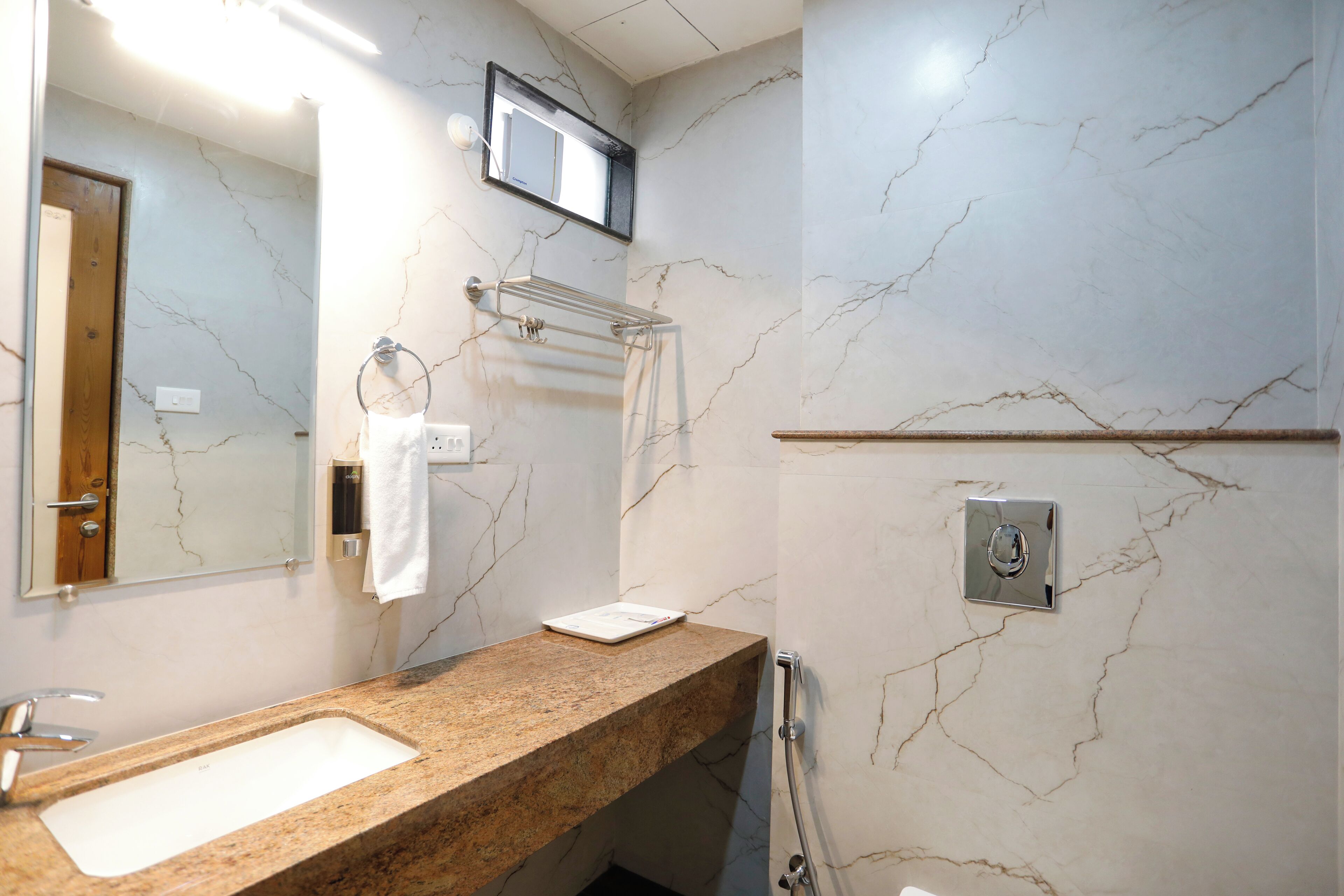 A bathroom with a marble wall, a sink, a towel rack, and a mirror.