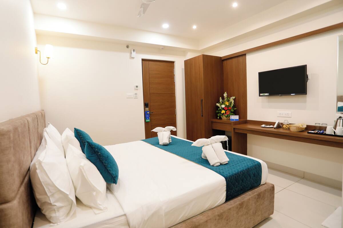 Una habitación de hotel con cama, escritorio, televisor y puerta del baño.