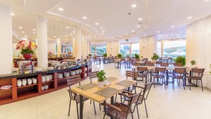 A spacious dining area with multiple tables and chairs, a buffet counter with various food items, and large windows offering a view of the outdoors. - Dalat Wonder Resort (Xuan Huong - Da Lat)