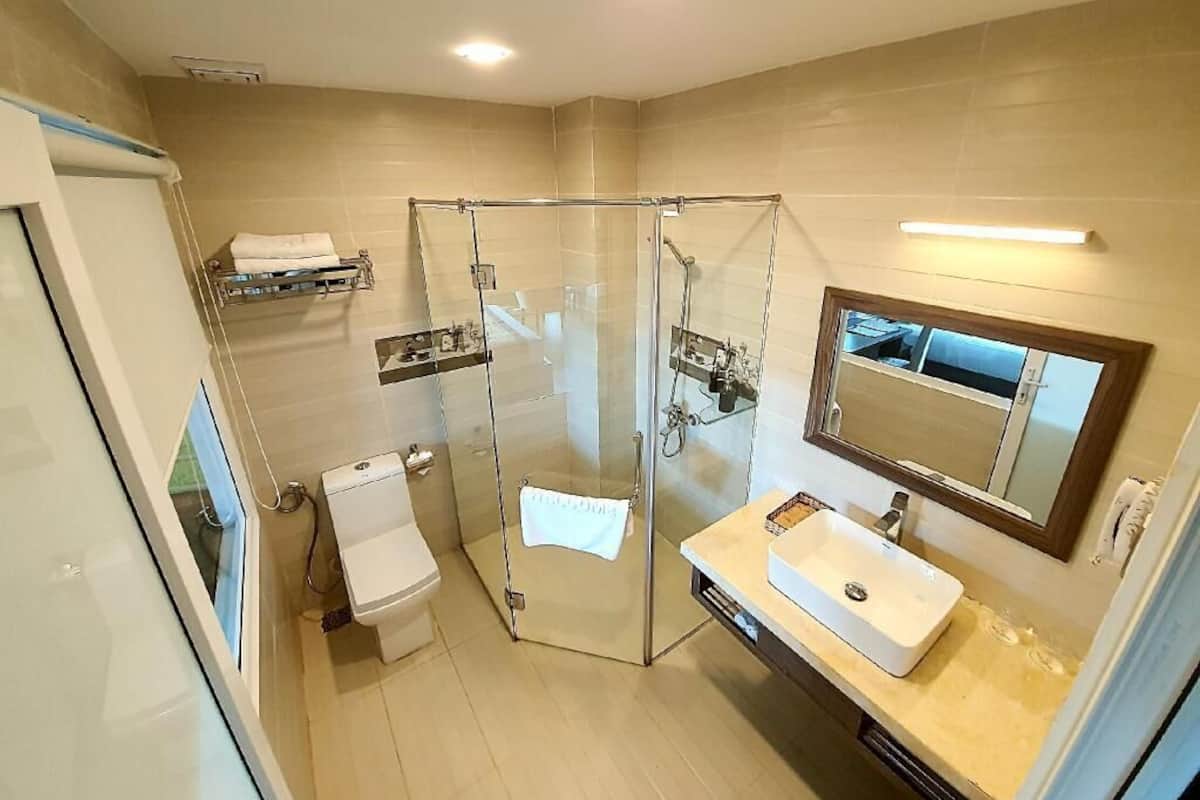 Une salle de bain moderne avec une douche à parois de verre, des toilettes blanches et un meuble-lavabo avec un miroir.