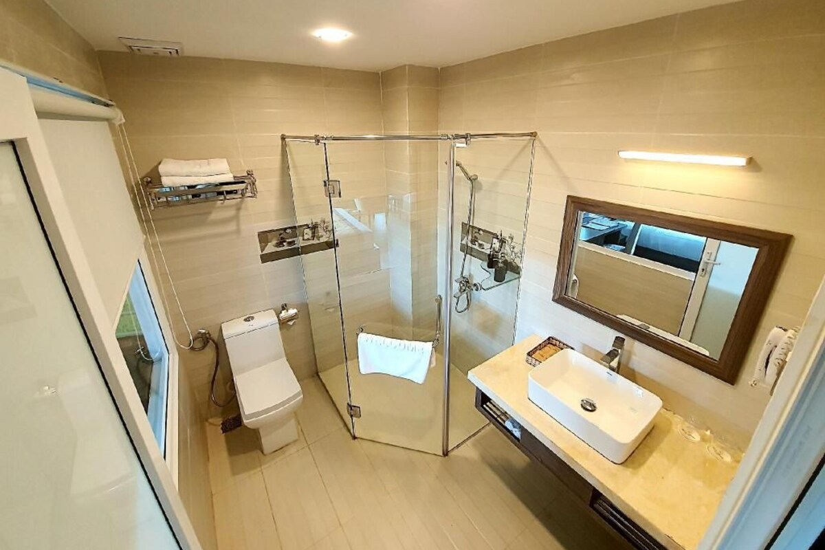 Un baño moderno con cabina de ducha de vidrio, inodoro blanco y tocador con espejo.