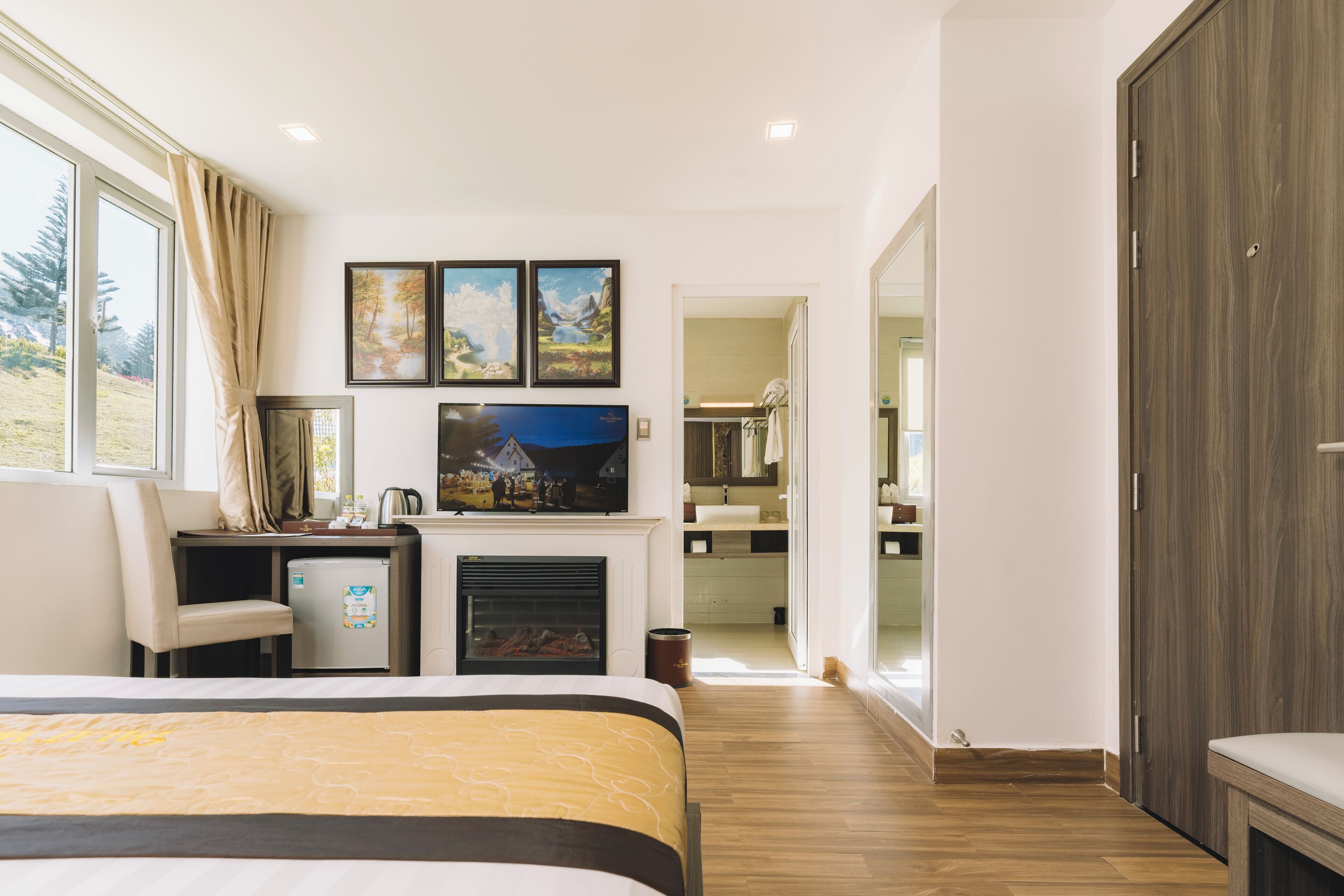 A hotel room with a bed, a desk, a television, and a fireplace.
