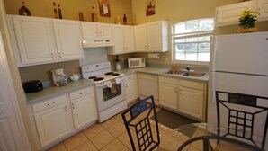 A compact kitchen with white cabinets, a stove, a microwave, and a refrigerator. - Ly53766 - Indian Ridge - 4 Bed 2 Baths Villa (Kissimmee)