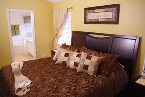 A bedroom with a bed, a nightstand, a framed sign on the wall, and a bathroom visible through an open door. - Ly53766 - Indian Ridge - 4 Bed 2 Baths Villa (Kissimmee)