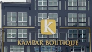 Un edificio de hotel con un llamativo letrero que dice 'KAMPAR BOUTIQUE HOTEL'.