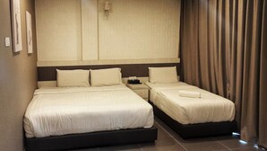 Habitación de hotel con dos camas, una mesita de noche y un ventanal con cortinas.