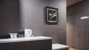 Un baño moderno con una encimera blanca, una cafetera y un cuadro en la pared.
