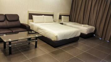 Quarto de hotel com duas camas, um sofá e uma mesa de centro de vidro.