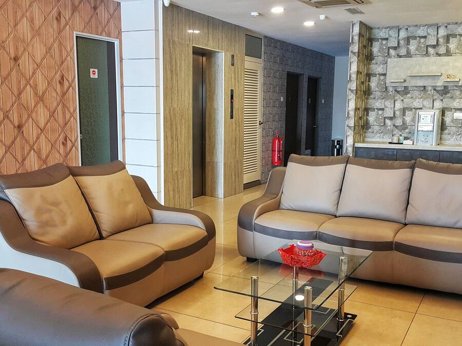 A modern living area with two sofas, a glass coffee table, and a kitchen area with a stone backsplash.