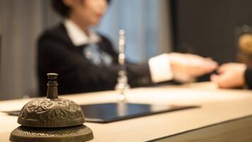 A reception desk with a decorative object on it, a tablet, and a blurred figure in the background.