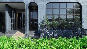 Una entrada de hotel moderna con un letrero que dice "HOTEL AREAOne", una puerta de vidrio y bicicletas estacionadas afuera.
