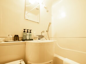 Un baño con lavamanos, espejo y artículos de aseo.
