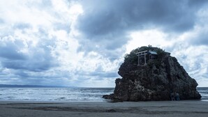 Un saliente rocoso con un tradicional torii japonés en la cima, con vistas al mar.