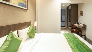 Une chambre d’hôtel avec un lit, un bureau, une chaise, une lampe et un tableau au mur.