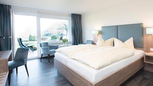 Une chambre d’hôtel moderne dotée d’un grand lit, d’un bureau et d’un balcon avec des chaises.