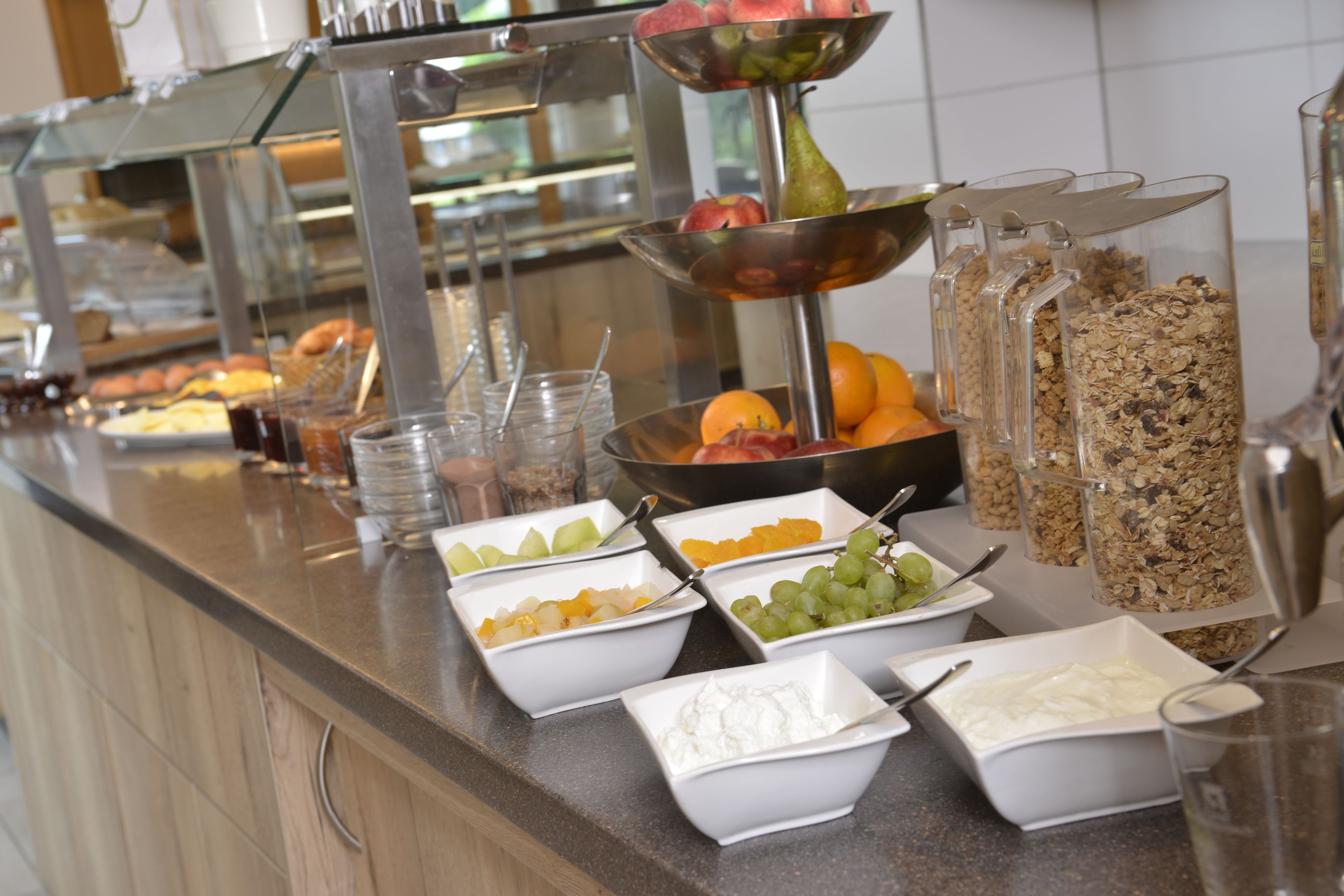 A buffet with various food items including fruits, vegetables, and cereals.