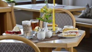 Une table à manger avec un gâteau, une tasse de thé et une bougie.
