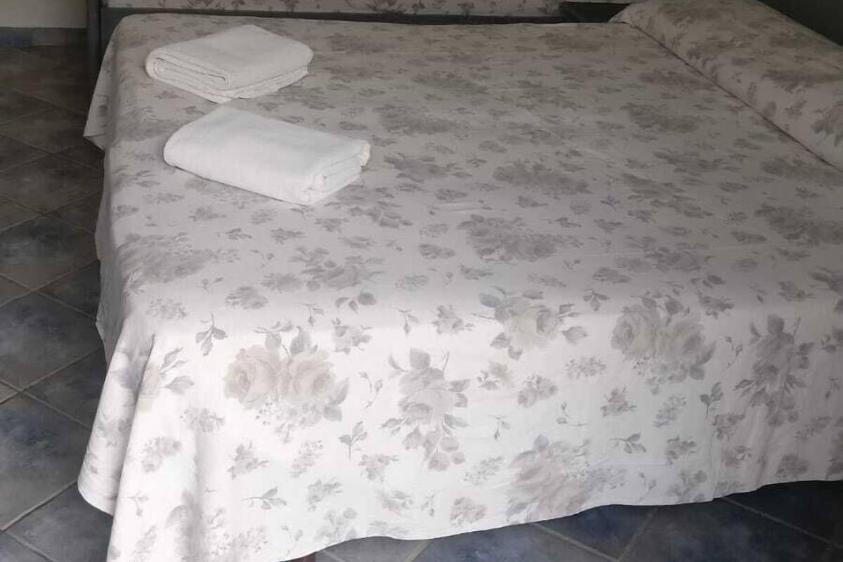 A room with two beds, each with a floral bedspread and neatly folded towels.