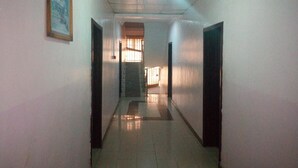 A narrow hallway with a tiled floor, white walls, and a framed picture on the left. - Bayse One Executive Suites and Bar (Ibadan)