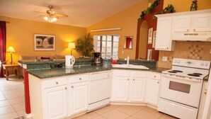 A kitchen with white cabinets, a stove, and a coffee maker.