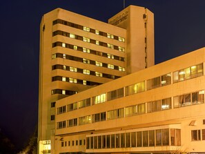 A multi-story hotel with a modern architectural design, featuring a prominent signage at the top.