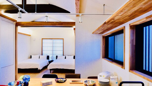 A modern kitchen with a central island, wooden beams, and a large window. - Cochi-en (Kyoto)