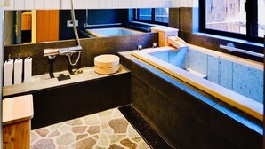 A modern bathroom with a bathtub, shower, and a large mirror. - Cochi-en (Kyoto)