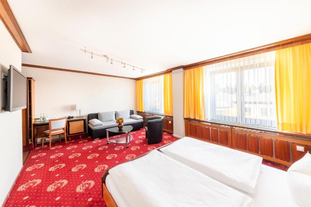 Una habitación de hotel con cama, escritorio, silla, sofá y televisión.