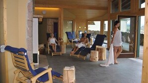 Un salón interior con luz natural, muebles de madera y una puerta de vidrio que da al exterior.