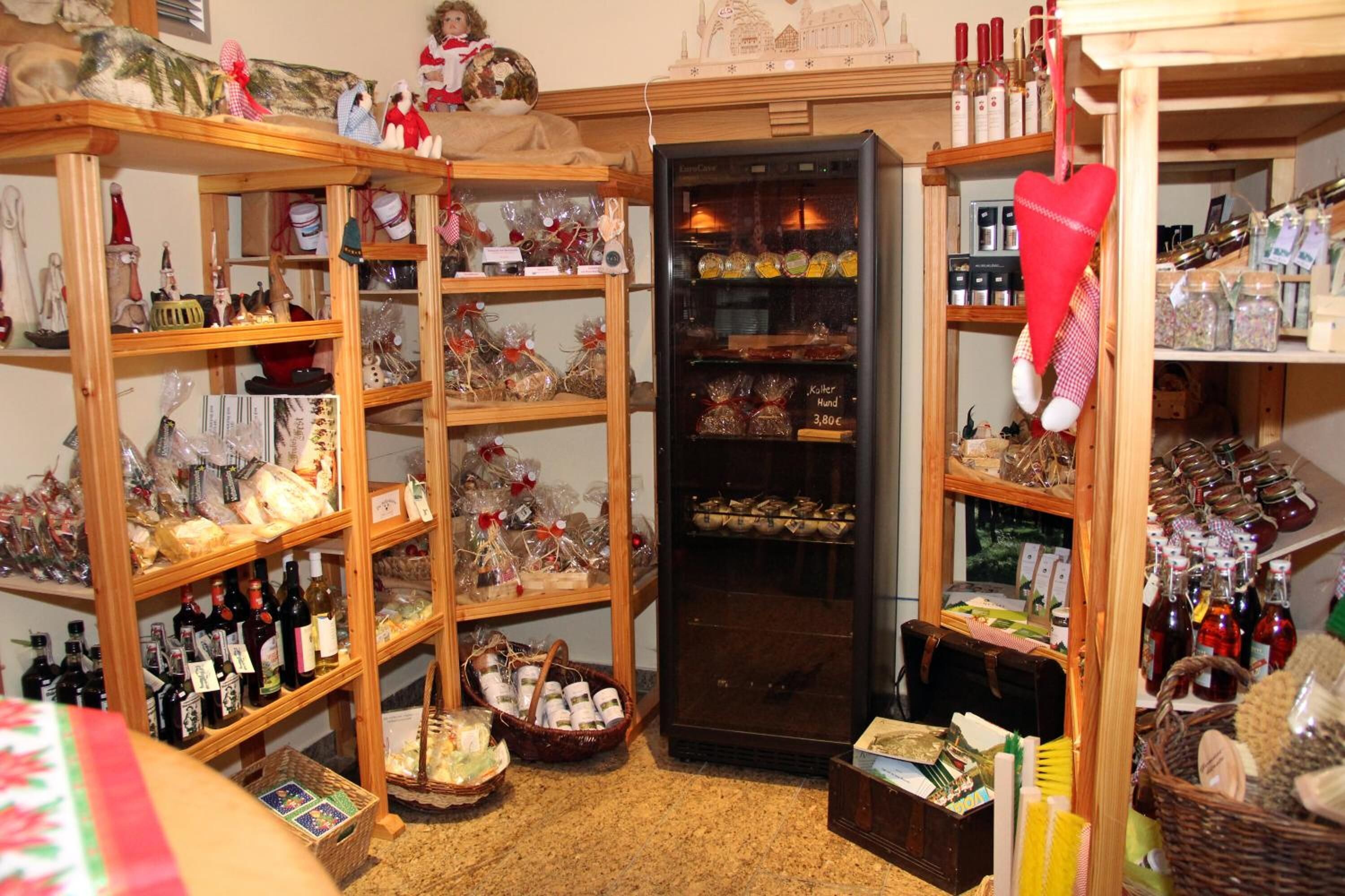 Une petite boutique chaleureuse, avec des étagères en bois remplies de divers articles, comme des bouteilles, des paniers et des objets décoratifs.