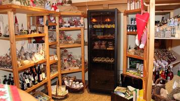 Een kleine, gezellige winkel met houten planken vol diverse producten zoals flessen, manden en decoratieve objecten.