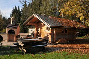 A rustic log cabin with a chimney, a wooden bench, and a picnic table in front. - Hotel Forstmeister (Schoenheide)