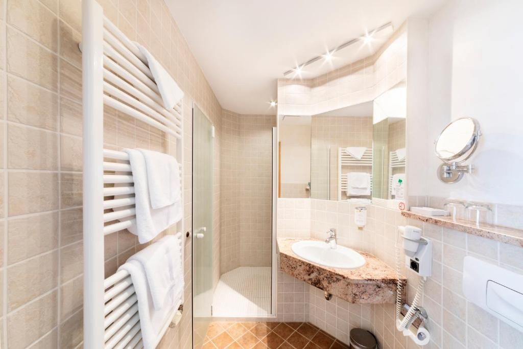 A modern bathroom with a glass shower enclosure, a marble sink, and a large mirror.