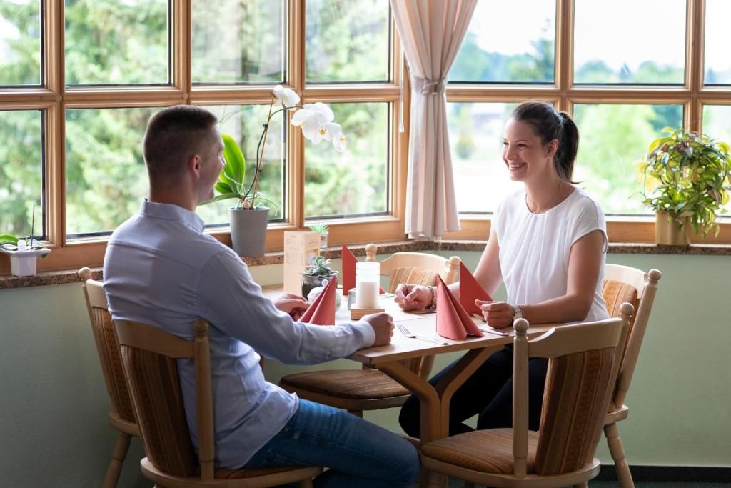 A dining area with a table set for two, surrounded by chairs, with a window view.