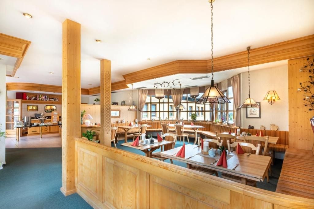 A spacious dining area with wooden furniture and pendant lighting.