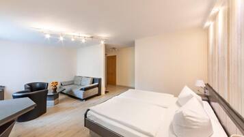 Una habitació d'hotel moderna amb un llit gran, un sofà, un escriptori i una cadira.