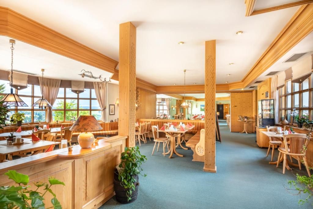 A spacious restaurant with wooden furniture and large windows.