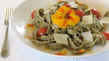 A plate of pasta with cherry tomatoes and a flower garnish.