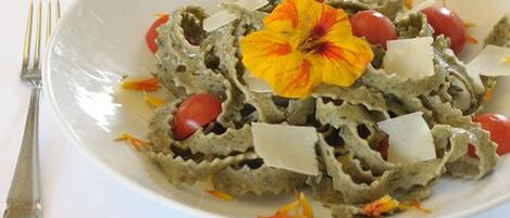 A plate of pasta with cherry tomatoes and a flower garnish.