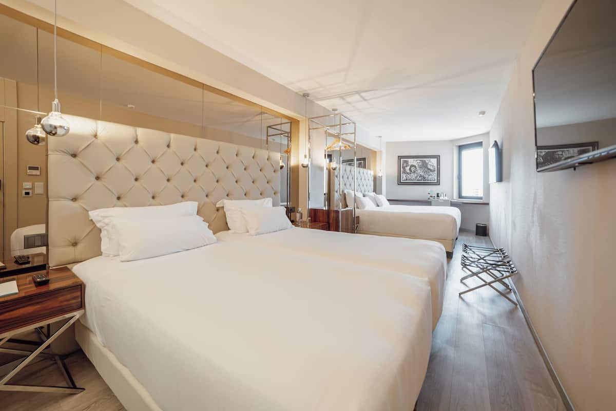 Ett hotellrum med två sängar, en stor spegel, en garderob och en klädstång.