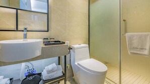 A modern bathroom with a sink, toilet, and glass shower enclosure. A towel hangs on the shower door, and a sign indicates the hotel name. - Xana Lite Hotelle Shunyi (Shunyi)