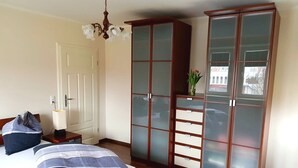 Makuuhuoneessa on sänky, yöpöytä, himmeälasisilla ovilla varustettu vaatekaappi ja kattokruunu.
