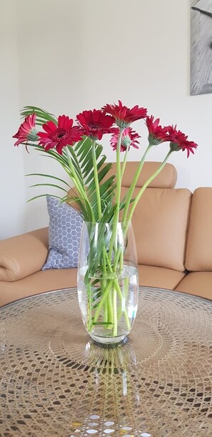 A clear glass vase with red flowers on a round table. - Apartment on the Elbe Ferry - Apartment for 2 - 3 People (Dresden)