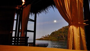 A room with a view of a body of water and a forested island. - Raja Ampat Dive Lodge (Mansuar Island)
