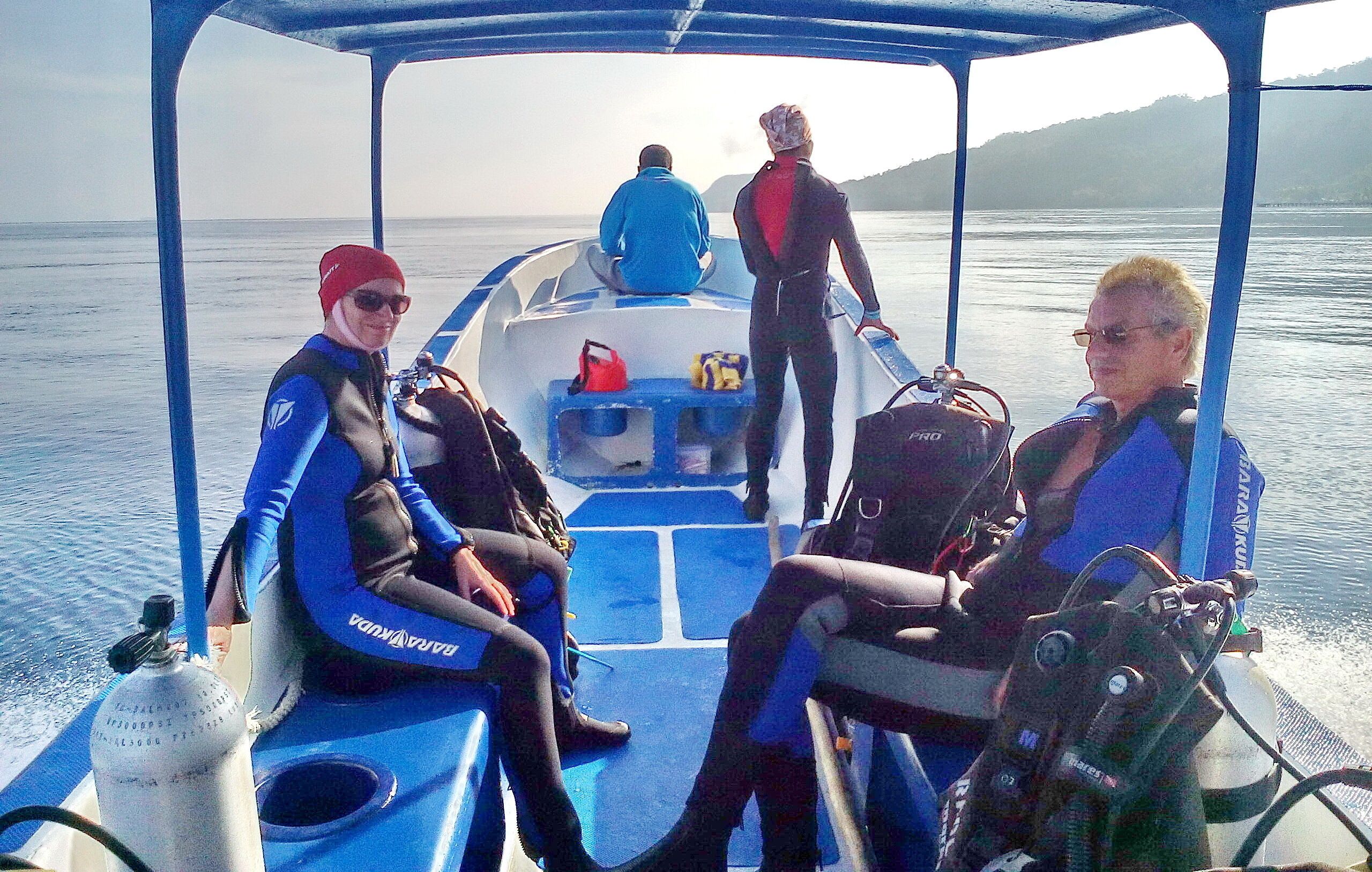 A boat with passengers wearing diving gear, a steering wheel, and a life jacket.