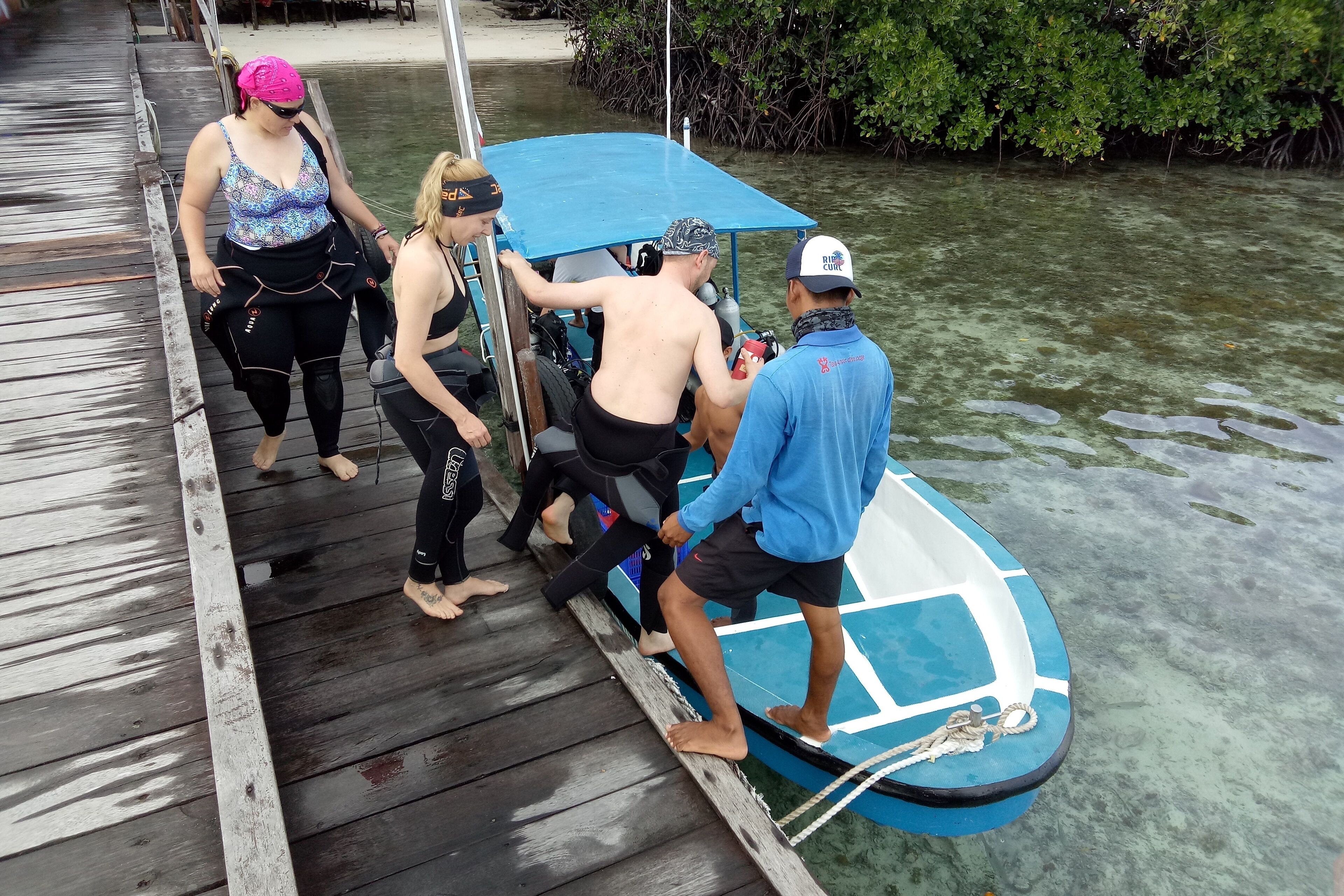Un grupo de personas subiendo a un bote desde un muelle de madera.